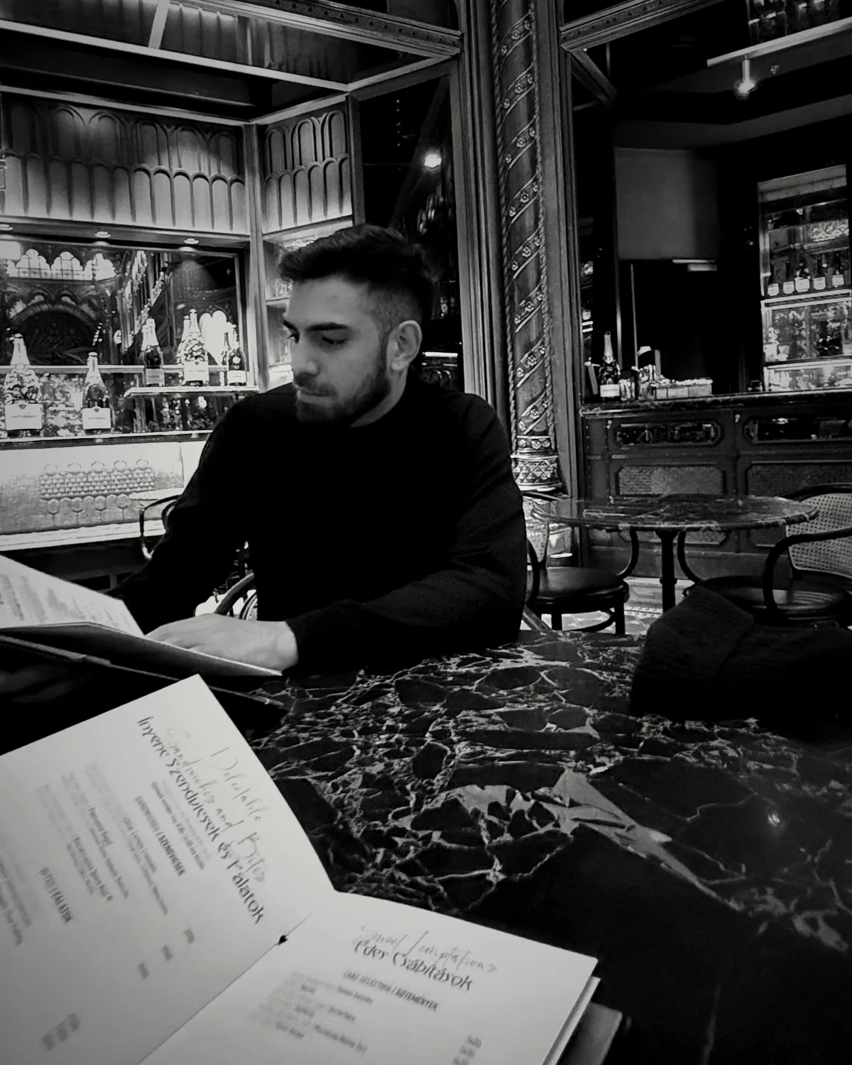Nahuel Ponce leyendo en un café, en blanco y negro